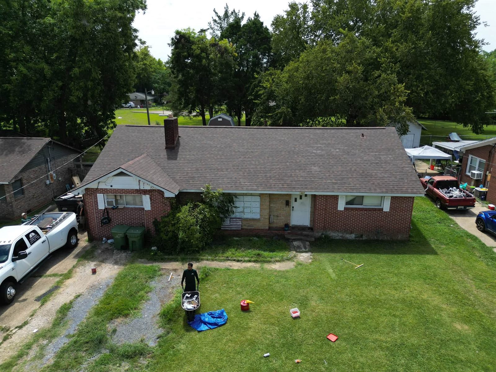 Crew member cleaning up the yard of a brick ranch home after its new roof