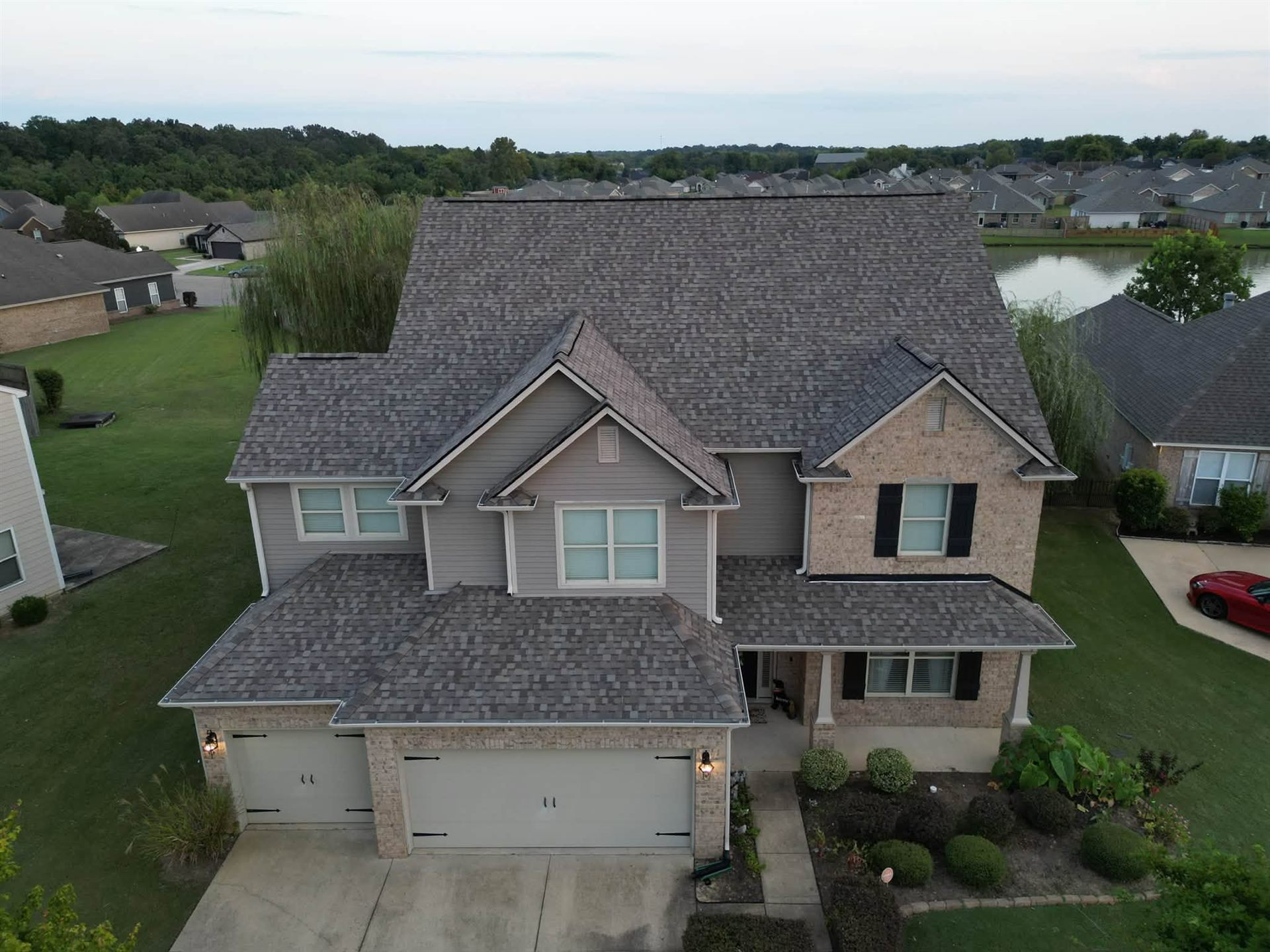 Drone view of a two-story Montgomery home with a new shingle roof by Raymundo's Roofing