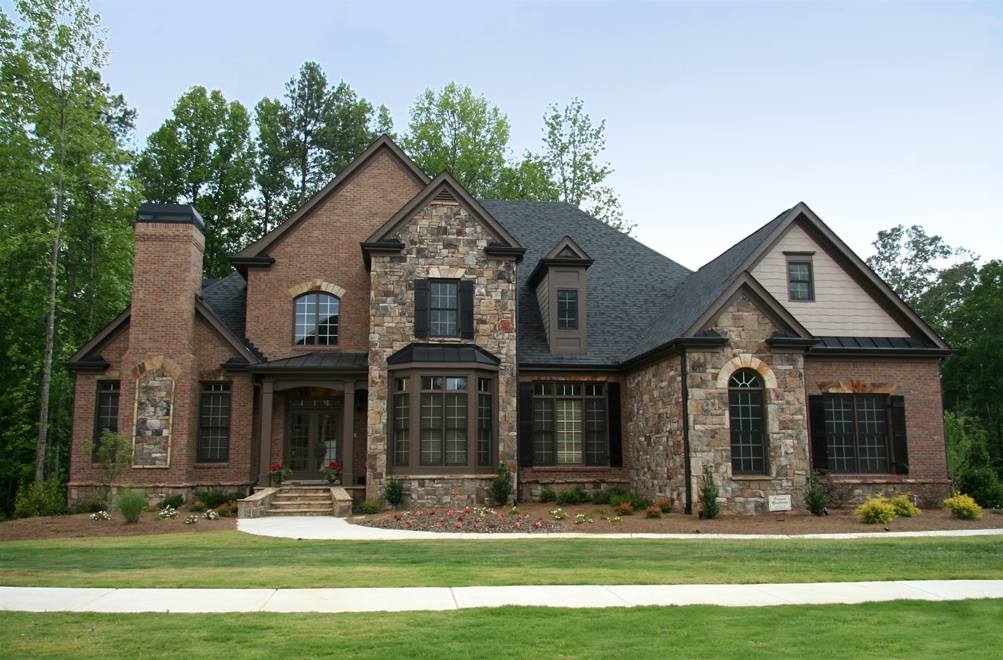 Brick and stone two-story home with a dark shingle roof